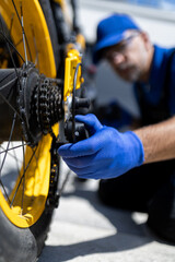 Close up of technician adjusting rear derailleur on electric bicycle drivetrain