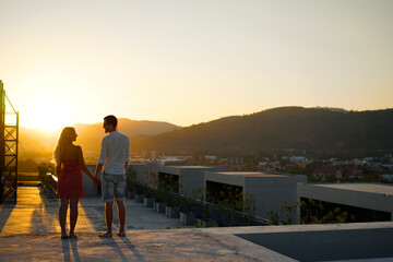 Fototapeta premium Couple Enjoying Sunset Views on a Rooftop Terrace Overlooking a Cityscape