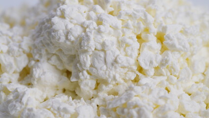 Texture of soft cottage cheese granules, Macro view highlighting grainy cottage cheese texture, Closeup image showcasing creamy cottage cheese curds packed in bowl