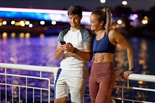 Fitness couple taking a break using smartphone