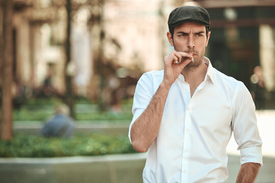 Man in flat cap smoking cigarette outdoors