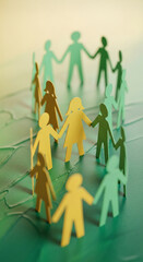 Paper figure of person holding hands in a circle, symbolizing unity and community on a green textured surface, representing teamwork and collaboration