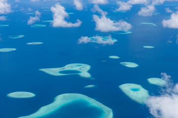 Obraz premium Maldives aerial drone view of turquoise ocean with coral reef atolls and sparkling sunlight, pristine exotic tropical paradise beach scenery perfect for travel vacation