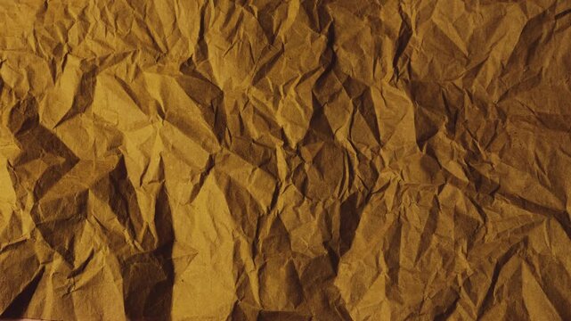 Crumpled sheets of handmade paper in warm terracotta and sandy beige tones are being placed on top of each other. This vintage kraft paper texture showcases a rough.