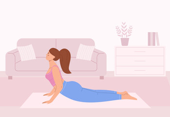 Young female practicing yoga. Woman in cobra pose in a cozy living room on a mat. Interior background for flexibility, fitness, health and relaxation lifestyle design.