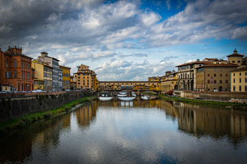 Fototapeta premium View of Ponte Vecchio over the Arno River in Florence during late afternoon with clouds in the sky