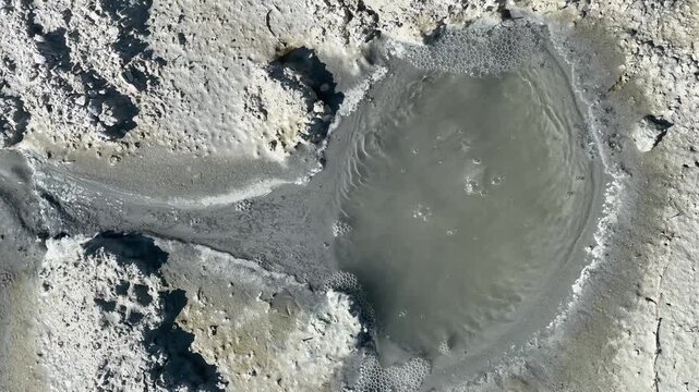 Close-up detail of small water sources naturally bubbling up from gray mud along the shore of Lake Burdur, forming bubbles on the surface. Natural geothermal activity landscape.