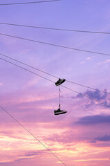 A pair of shoes hang from a power cable as the sun sets