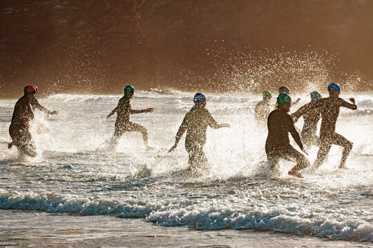 A group of swimmers run into the sea at the start of a competitive race