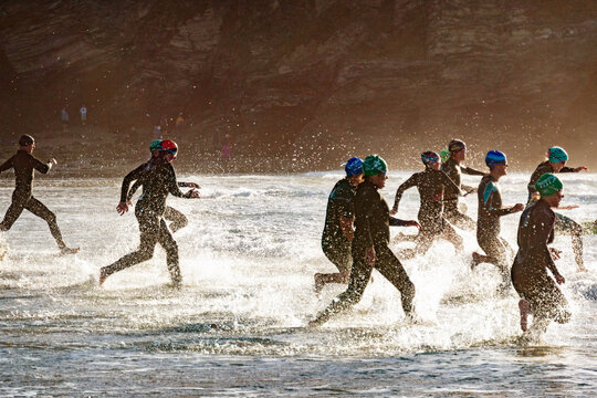 A group of swimmers run into the sea at the start of a competitive race