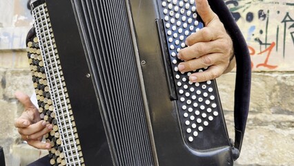 Male hands of musician playing the accordion at urban street. The detailed view highlights texture of instrument, capturing rhythm, tradition, and the expressive character of live music performance