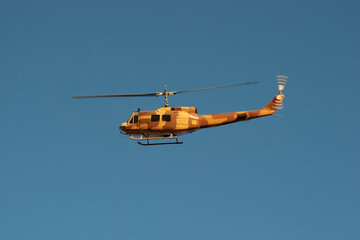 Camouflage military helicopter flying in a clear blue sky, concept for defense industry, aviation, and tactical operations