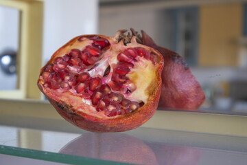 Fresh Pomegranate Cut in Half on Glass Surface - Juicy Red Seeds Close Up