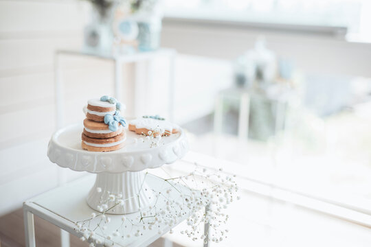 Elegant baby baptism celebration details featuring a decorated cake, baby shoes and soft pastel decorations. Concept of newborn milestone, family celebration, christening ceremony, love