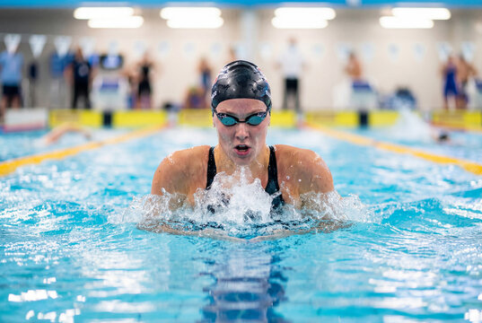 Female swimmer doing breaststroke in a swimming pool during a competition