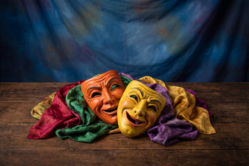 Fototapeta na wymiar Comedy and tragedy theater masks on wooden table with colorful cloth
