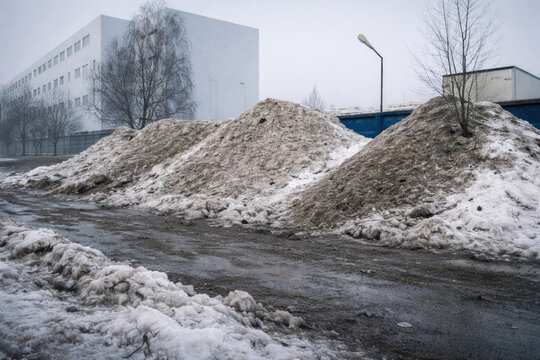 Dirty Snow Piles in Urban Industrial Area During Winter Thaw