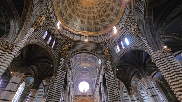 Low angle view of the ornate dome and striped marble columns inside Siena Cathedral (Duomo di Siena), Tuscany, Italy