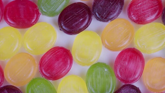 Bright overlapping round candies with powdered sugar highlights and festive feel. Closeup of multicolored glossy candies with festive mood suitable for packaging and advertisements