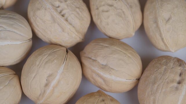 Closeup of rugged shelled walnuts on neutral backdrop. Highquality image capturing rough shelled walnuts against beige background suitable for food branding and rustic markets