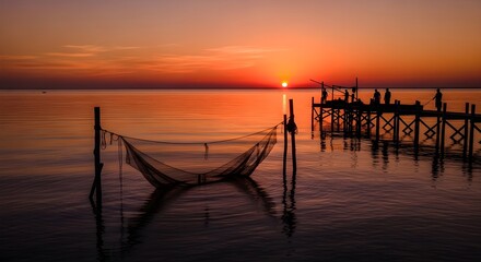 silhouette of fishing net on calm water at sunset