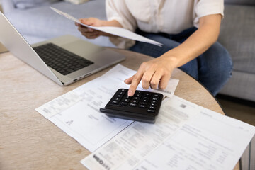 Young woman checking paper bills on calculator, counting expenses, monthly spending, personal...