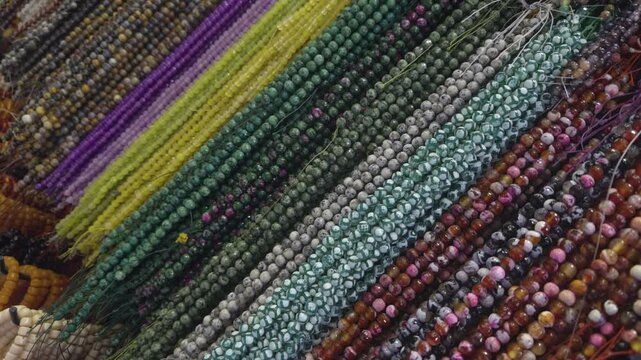 Rows of colorful beaded necklaces displayed on a market stall. Vibrant handmade jewelry textures create a rich visual background of fashion accessories, craftsmanship and artisan culture.