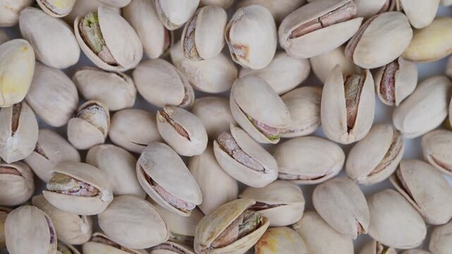 Salted pistachios closeup. Close view of salted pistachios with green kernels. Detailed closeup of salted pistachios in their shells highlighting organic textures and flavors
