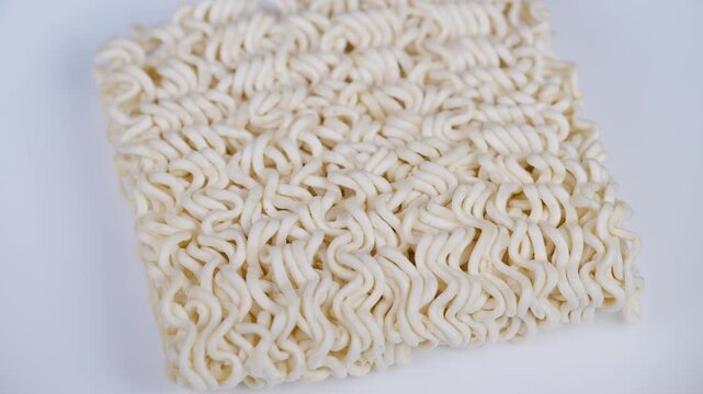 Intricate wheatcolored noodle macro shot. Detail of wavy dried noodles on white background. Studio macro image capturing detailed woven pattern and wavy texture of dried noodles