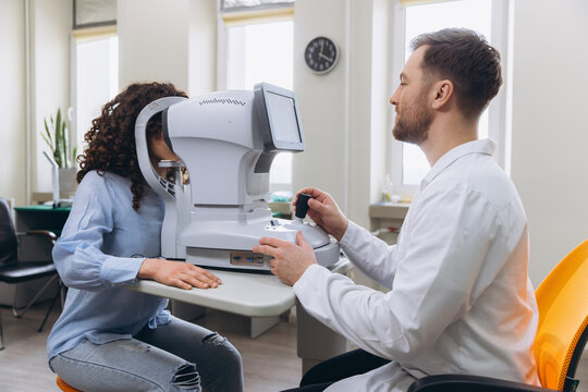 Optometrist performing an eye exam on a patient using an ophthalmic autorefractor in a vision clinic