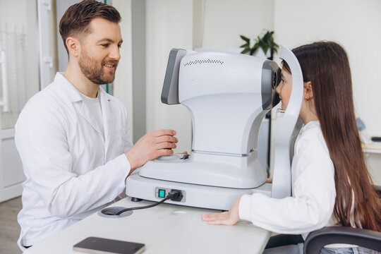 Eye doctor checking young girl's vision with automated refractor during ophthalmology consultation