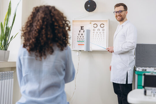 Ophthalmologist conducting eye vision test for patient using Snellen chart and Landolt C chart in clinic