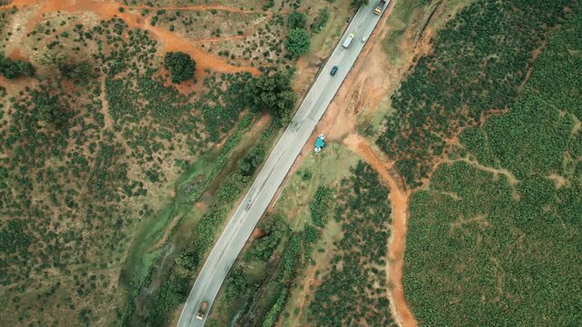 Cinematic drone aerial view of a winding road through lush tea gardens and forest hills in Jaflong, Sylhet, Bangladesh. Peaceful countryside landscape with clouds gathering