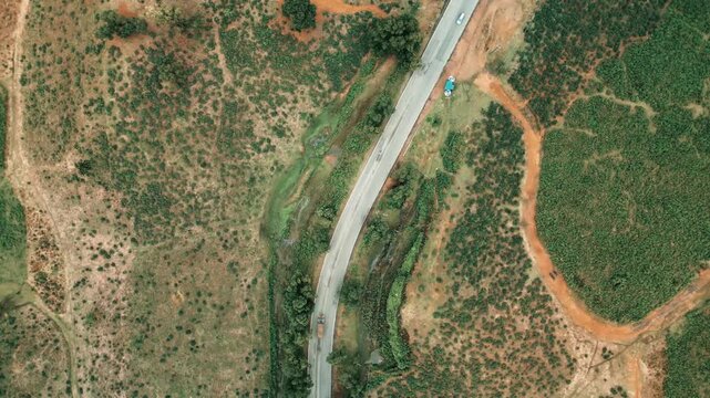 Cinematic drone aerial view of a winding road through lush tea gardens and forest hills in Jaflong, Sylhet, Bangladesh. Peaceful countryside landscape with clouds gathering