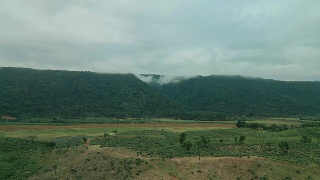 Cinematic drone aerial view of a winding road through lush tea gardens and forest hills in Jaflong, Sylhet, Bangladesh. Peaceful countryside landscape with clouds gathering