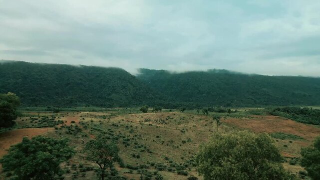 Cinematic drone aerial view of a winding road through lush tea gardens and forest hills in Jaflong, Sylhet, Bangladesh. Peaceful countryside landscape with clouds gathering