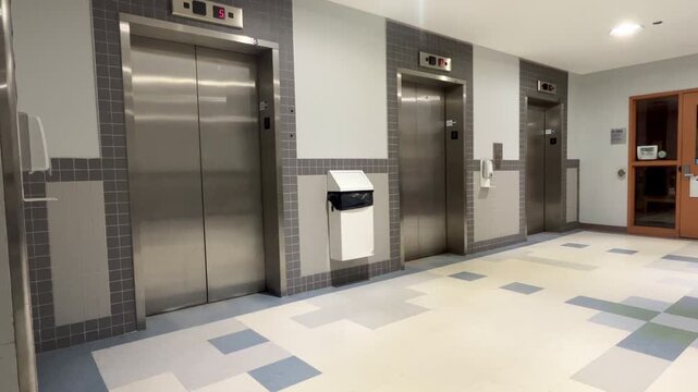 Modern hospital elevator lobby with stainless steel doors.