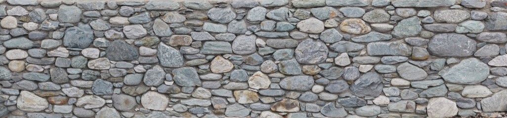 Rustic natural stone wall in panorama format.