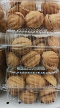 Traditional walnut-shaped cookies with boiled condensed milk filling in plastic containers on a supermarket shelf. Classic sweet snacks and pastries for sale in retail store. Tasty dessert concept