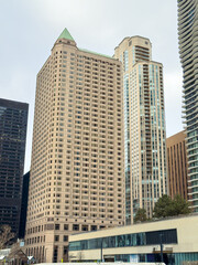 Fototapeta premium Tall buildings in a city skyline during a cloudy day with various architectural styles visible in the scene