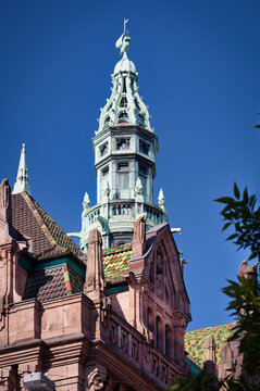 Architectural detail of the Stahlhof in Dusseldorf, a landmark of industrial history with an ornate green copper tower with a three-masted ship (cog) weathervane and colorful roof tiles