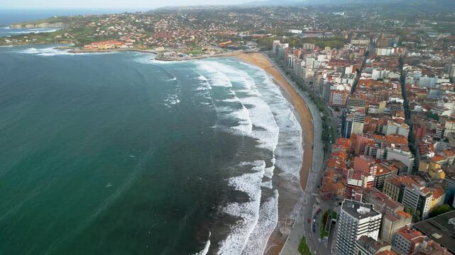 Aerial panoramic 4K view of San Lorenzo beach and Gijon city skyline, Asturias, Spain