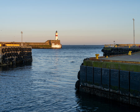 Fraserburgh Harbor entrance with iconic North Pier Lighthouse in Aberdeenshire, Scotland, on a calm evening