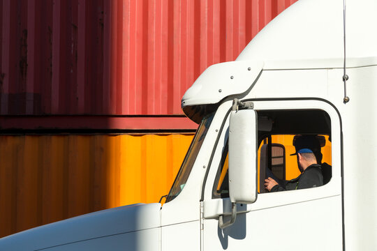 Canada, BC, Delta.  Truck driver in cab of his vehicle at container terminal.