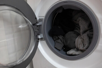 Open washing machine with clothes inside drum ready for laundry cycle. Modern household appliance used for washing garments, representing domestic chores, home care and everyday life