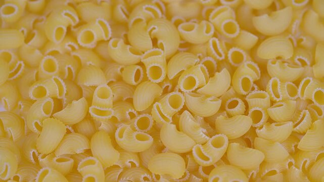 Closeup of pasta filling frame with cozy kitchen atmosphere. Detailed photograph showcasing yellow elbow macaroni in warm culinary environment for packaging or recipes
