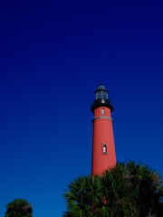 Tropical Palm trees grace the property around the Ponce Lighthouse on Florida's Atlantic coast on a blue sky perfect afternoon