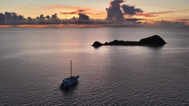 A serene sunrise silhouettes a small island in the Vatu-i-ra seascape in Fiji. This area is a marine protected area known for its high biodiversity and is a destination for divers and snorkelers.