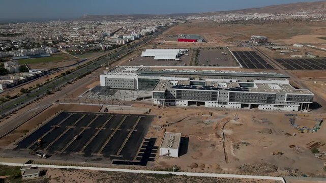 Vue a&eacute;rienne par drone d'un grand b&acirc;timent moderne et d'une infrastructure en construction avec des panneaux solaires sur le toit &agrave; Agadir, Maroc.