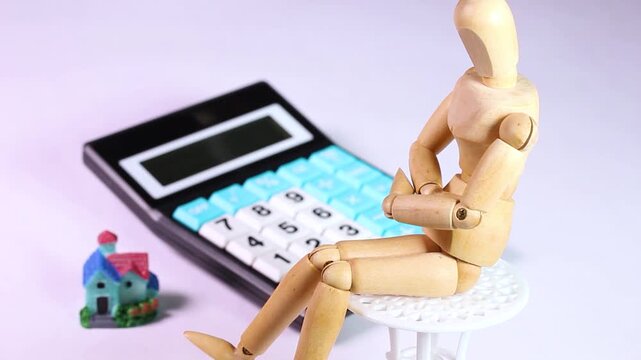 ミニチュアハウスと電卓と腕を組む木製人形　回転
